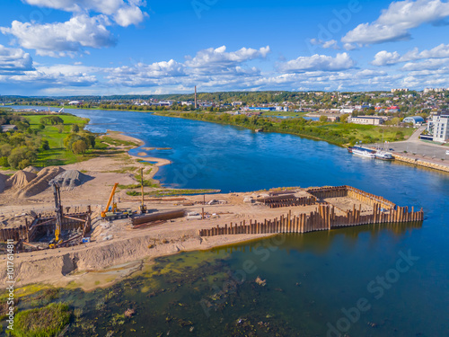 Construction site of new modern bridge construction in Kaunas, Lithuania. Aerial drone view of bridge connecting two shores of a river. Work progress