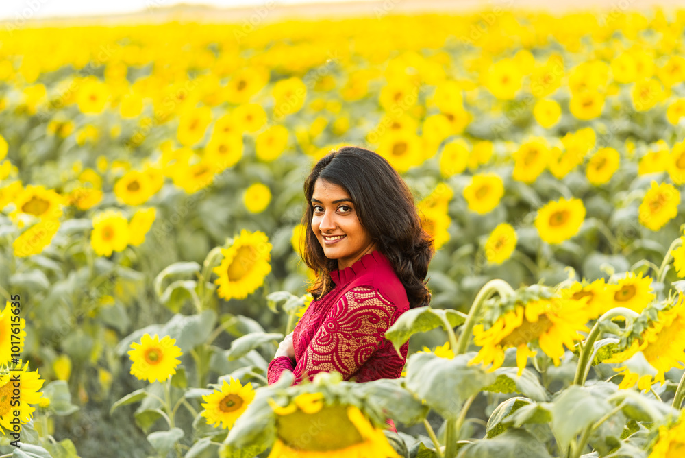 Smiling woman standing in a vibrant sunflower field at golden hour. Smiling woman standing in a vibrant sunflower field at golden hour.