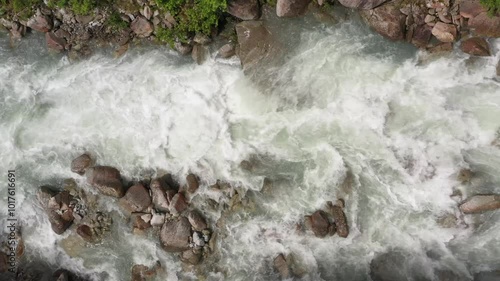 Clear stream running through stone boulders Abundant river flowing on stone bottom in slow motion. Aerial view of a pristine mountain river in Italy's Alps.