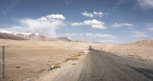 The asphalt road of the Pamir Highway winds and twists in the valley of the Tien Shan mountains in Tajikistan in Pamir, landscape in the high desert mountains for the background