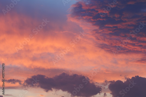 Cloudy sky and orange and pink sun lights reflecting from clouds