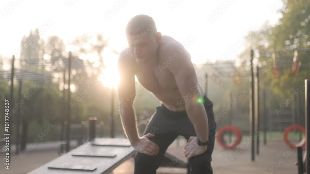 Exhausted Young Man Resting Outside on Gym Field, Naked Torso Exhausted Young Man Resting Outside on Gym Field, Naked Torso