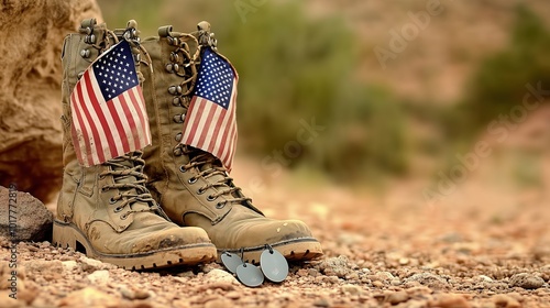 Worn old boots with dog tags and two small American flags resting on the ground in a desert landscape, symbolizing U.S. military service, sacrifice, and camaraderie. The rugged boots represent resilie photo