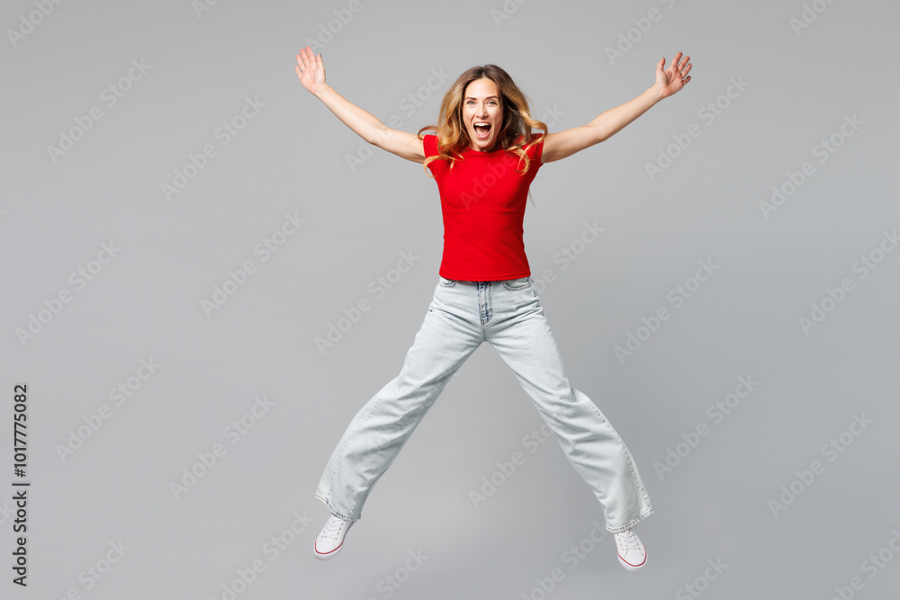 Full body young smiling excited happy woman she wear red t-shirt casual clothes jump high look camera with outstretched hands legs isolated on plain grey background studio portrait. Lifestyle concept. Full body young smiling excited happy woman she wear red t-shirt casual clothes jump high look camera with outstretched hands legs isolated on plain grey background studio portrait. Lifestyle concept.