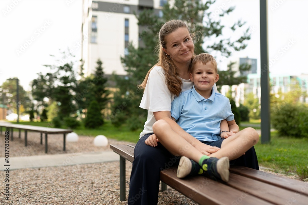 A joyful moment shared between mother and son sitting together in a park on a sunny day A joyful moment shared between mother and son sitting together in a park on a sunny day