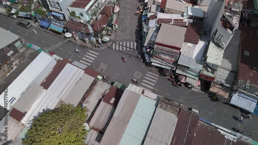 Drone flies over waterfront street and shanty tin rooftops of a densely populated area with top down view. Camera rotates to reveal traffic and modern buildings with strong light and shadows. Drone flies over waterfront street and shanty tin rooftops of a densely populated area with top down view. Camera rotates to reveal traffic and modern buildings with strong light and shadows.