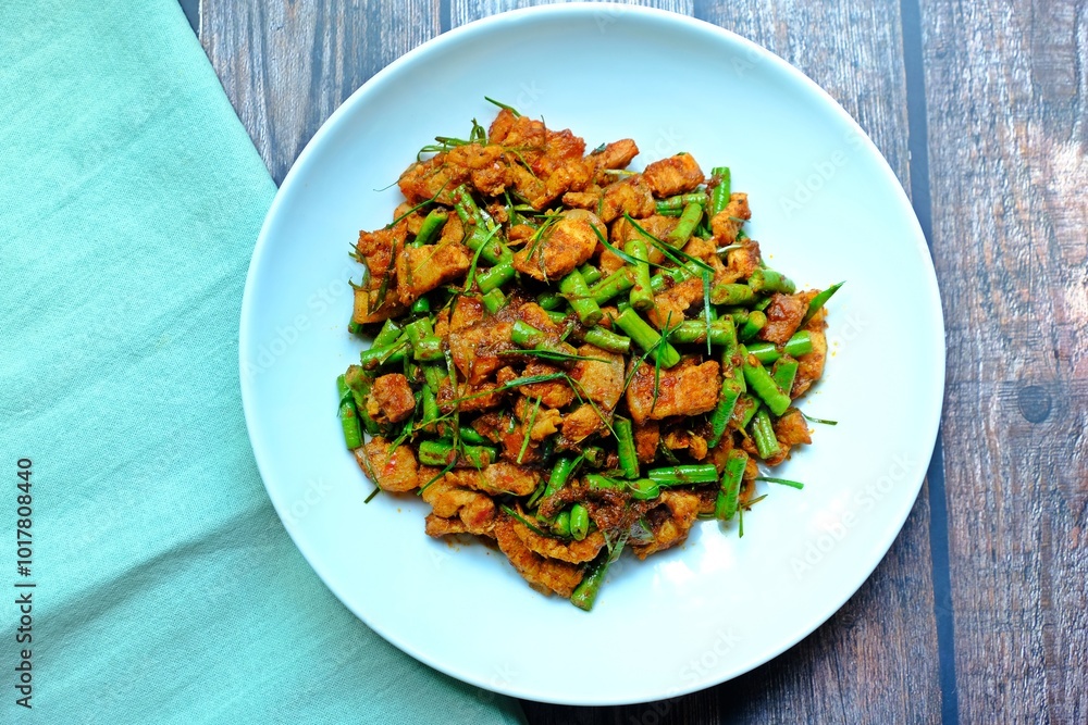 Stir fried crispy pork belly and yard long bean with ginger red curry paste, Authentic Thai food.