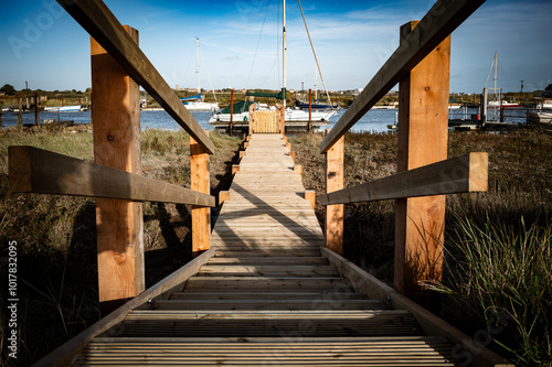 Dramatic view of a private timber jetty and gang plank leading to a large yacht moored in a English waterway close to the east coast. photo