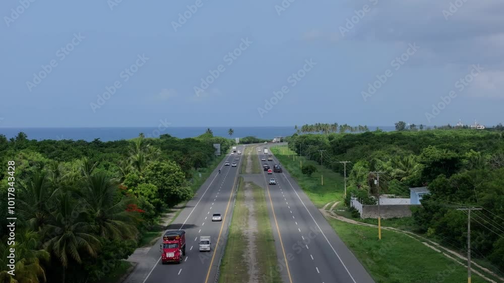 Aerial dolly of traffic and green fields on both sides with ocean out on horizon, Autopista Las Americas highway in the Dominican Republic Aerial dolly of traffic and green fields on both sides with ocean out on horizon, Autopista Las Americas highway in the Dominican Republic