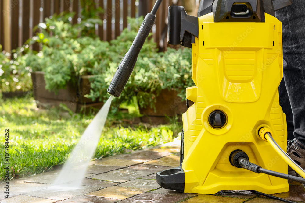 Fototapeta premium Washer Karcher. High Pressure Washing Paving Stones Blocks in Garden on Green Background. Cleaning Service.