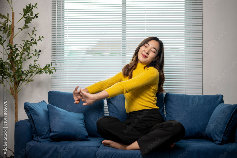 Young woman stretching her arms while sitting on a sofa at home Young woman stretching her arms while sitting on a sofa at home