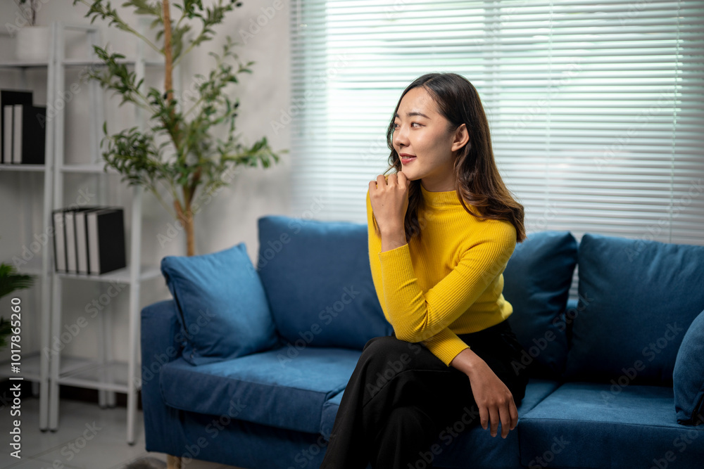 Young professional woman sitting on sofa pondering next steps in modern office Young professional woman sitting on sofa pondering next steps in modern office