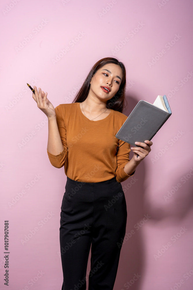 A woman is holding a book and a pen A woman is holding a book and a pen