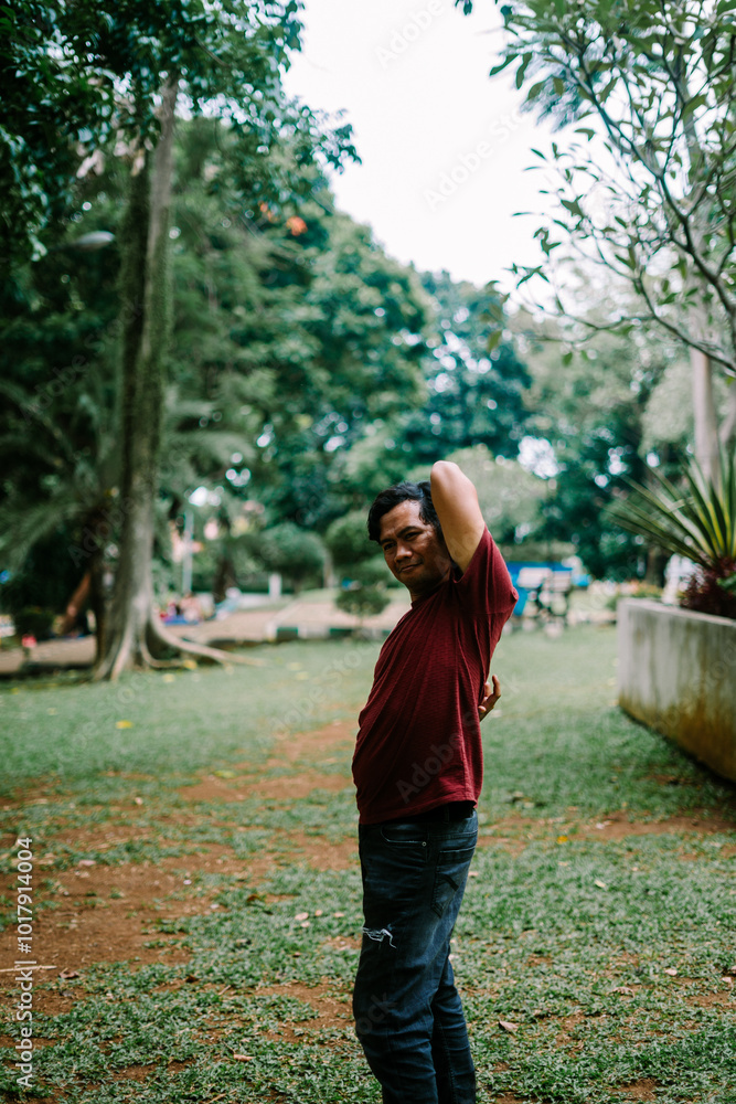 Fototapeta premium Southeast Asian man scratching his back, expressing discomfort from itching