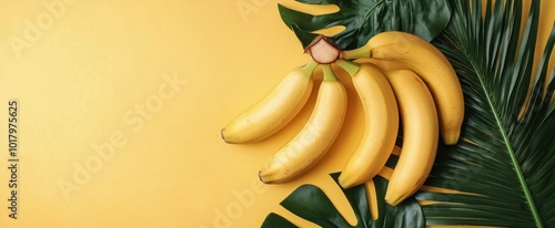 Yellow bananas with tropical leaves on vibrant yellow background in a bright ...
