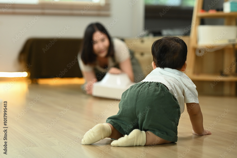 Cute baby boy crawling on the floor towards mother. Parenting, child development and family concept Cute baby boy crawling on the floor towards mother. Parenting, child development and family concept