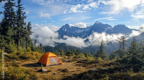 A lone orange tent sits in a clearing in a mountain forest, with a majestic view of snow-capped peaks behind it. The clouds are low, and the sun is shining.