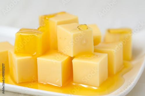 A plate honey and cheese with cubes. parmesan cheddar concept. a plate of sliced cheese and honey drizzled on top of a white. a plate of sliced cheese with honey drizzled on top of lifestyle it.