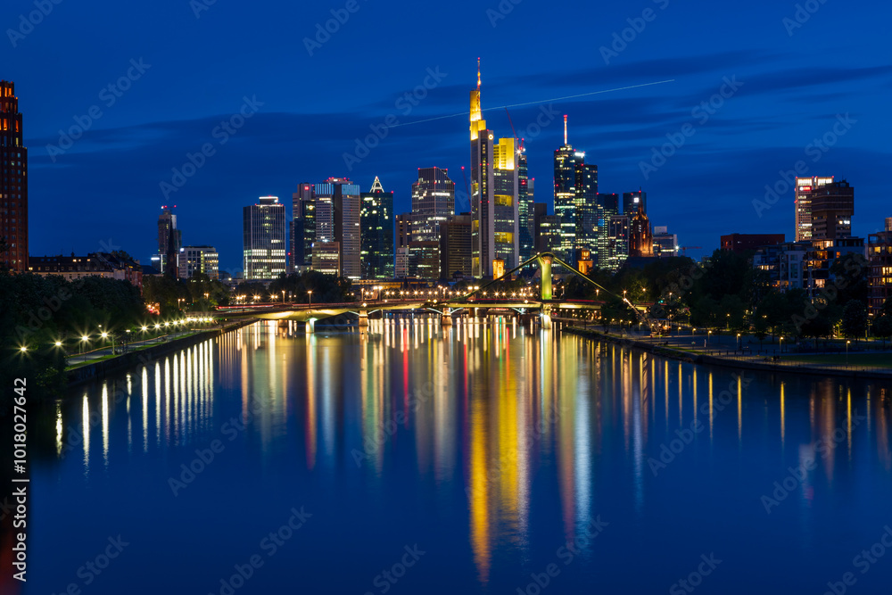 Naklejka premium Photo from Deutschherren Bridge in Frankfurt after sunset in blue hour. The city center and the river Main are lit in the background.
