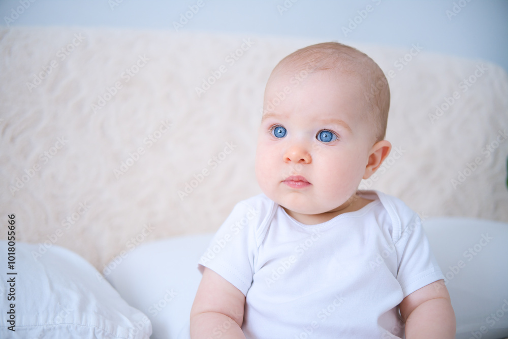 portrait of smiling healthy baby in white bodysuit sitting on bed. copy space portrait of smiling healthy baby in white bodysuit sitting on bed. copy space