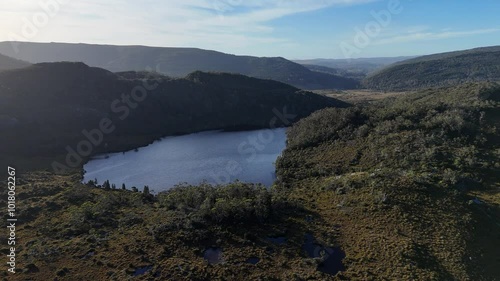 Aerial establishing shot of Crater Lake in St Clair National Park during sunset time. Mountain Cradle Area with green landscape. Wide shot. Tasmania, Australia. photo