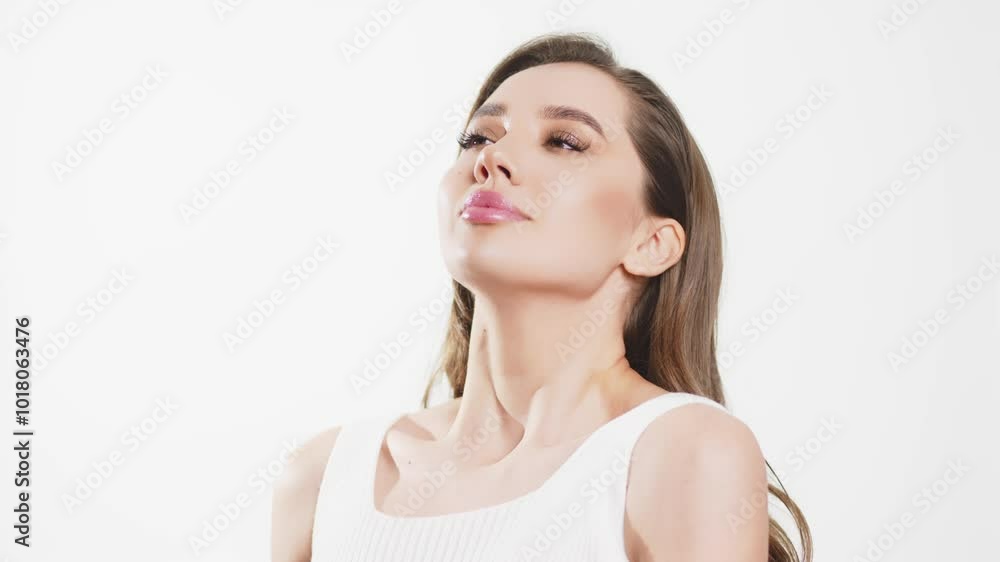 A charming young woman with light makeup holds and uses a spray bottle against a white background. This moment emphasizes the importance of daily skincare and beauty in every woman's life. A charming young woman with light makeup holds and uses a spray bottle against a white background. This moment emphasizes the importance of daily skincare and beauty in every woman's life.