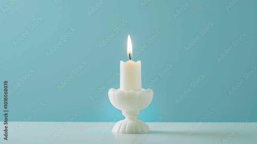 single white candle burns brightly in candlestick against light blue background single white candle burns brightly in candlestick against light blue background