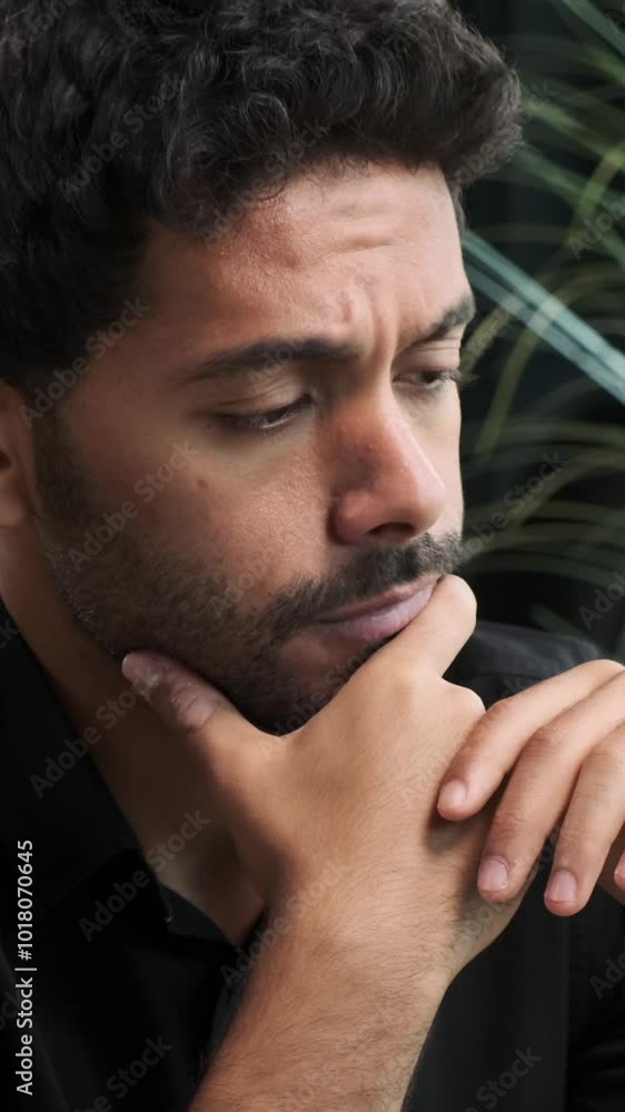 Portrait of a worried Middle Eastern young adult male employee lost in thoughts in the office. Frustration, sorrow and depression concept. Vertical video. Portrait of a worried Middle Eastern young adult male employee lost in thoughts in the office. Frustration, sorrow and depression concept. Vertical video.