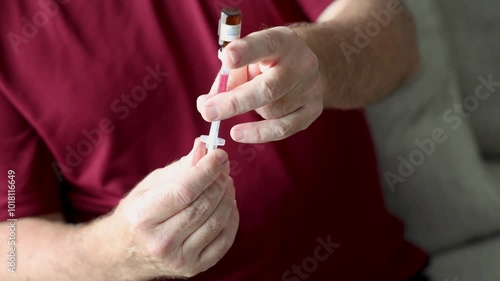 Man preparing to inject medication, possibly weight loss medication, using a syringe, focusing on hands and vial.