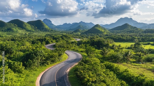 Wide view of a picturesque, winding road through a lush green landscape with scenic mountains in the distance