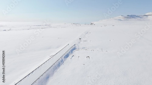 Slow aerial flight across untouched snowy landscape in Lesotho, Africa, over Sani Top village, border post, and along cliff edge of Sani Pass to reveal snowy mountain landscape in South Africa below
