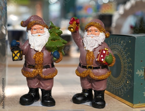 New Year's card with figures of Santa Claus in brown suits on the table near the green box with gifts photo