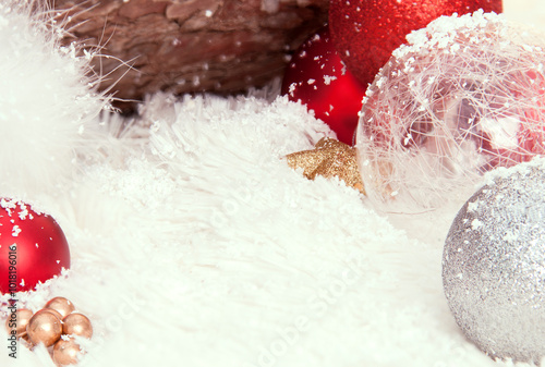 Landscape for Christmas card. White fur surface with snow and red and silver Christmas balls. Defocused tree trunk texture background