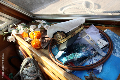 Still life corner of a ship with captain's hat, flowers, magazines and other related trinkets. Wood and ropes setting photo