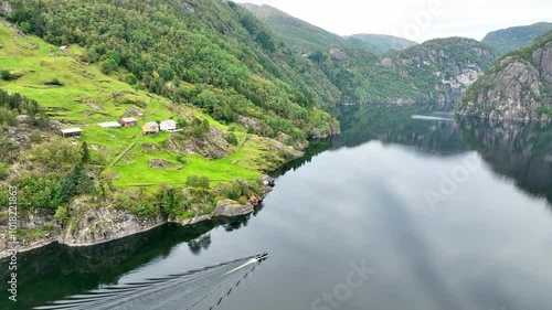 Pontoon boat cruising on a glossy fjord surface, Furnes farmland in the background, drone ascends to reveal the vast fjord landscape photo