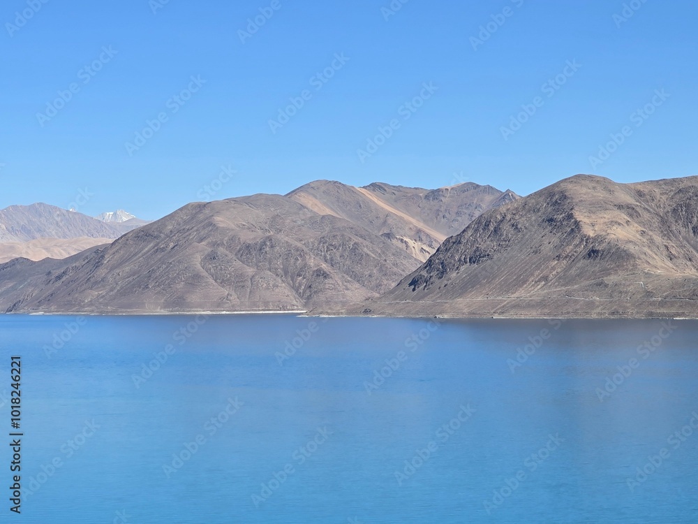 Serene Pangong Tso Lake: A breathtaking panoramic view of Pangong Tso lake in Ladakh, India, with its stunning turquoise waters reflecting the majestic mountains under a clear blue sky. Serene Pangong Tso Lake: A breathtaking panoramic view of Pangong Tso lake in Ladakh, India, with its stunning turquoise waters reflecting the majestic mountains under a clear blue sky.