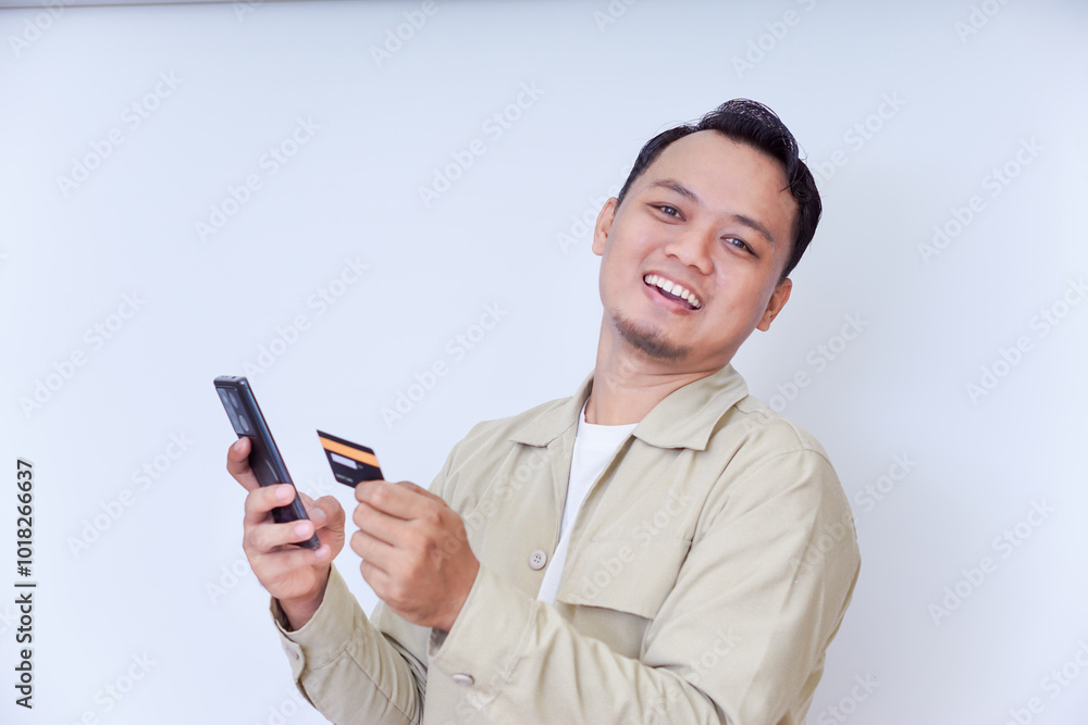 A cheerful man holding a smartphone and credit card, ready for a transaction. A cheerful man holding a smartphone and credit card, ready for a transaction.