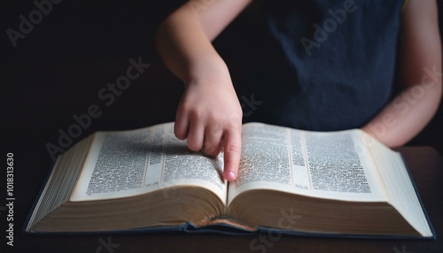 A child's small hand touching the center of an open Bible