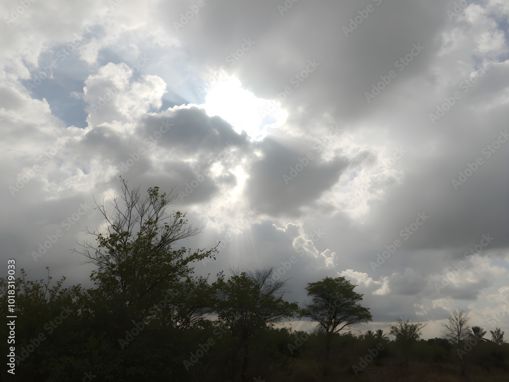 A cloudy day with the sun breaking through the clouds in a few places, creating bright sunbeams that illuminate patches of the ground A cloudy day with the sun breaking through the clouds in a few places, creating bright sunbeams that illuminate patches of the ground