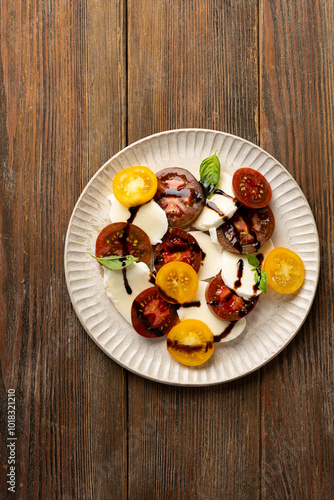 Caprese salad with sliced heirloom tomatoes and cheese on wooden surface