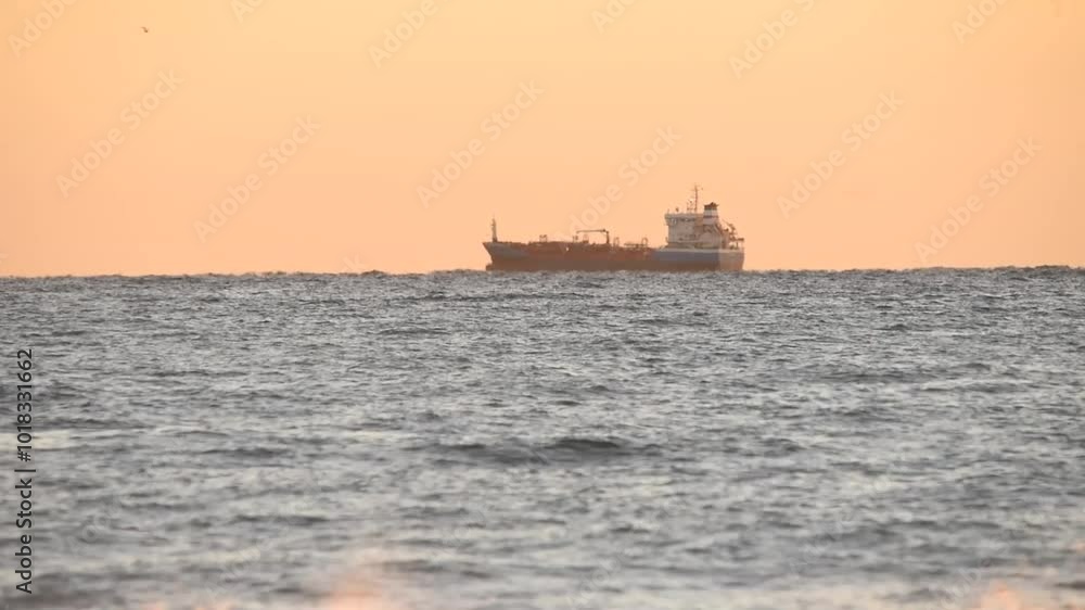 A freight ship sailing at dawn. Beautiful sunrise over the sea. The morning sun illuminates the sea. Dawn in the Mediterranean Sea. Sun reflections in the water, boat A freight ship sailing at dawn. Beautiful sunrise over the sea. The morning sun illuminates the sea. Dawn in the Mediterranean Sea. Sun reflections in the water, boat