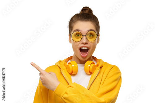 Foto Young shocked girl, wearing round glasses and headphones on neck, pointing left