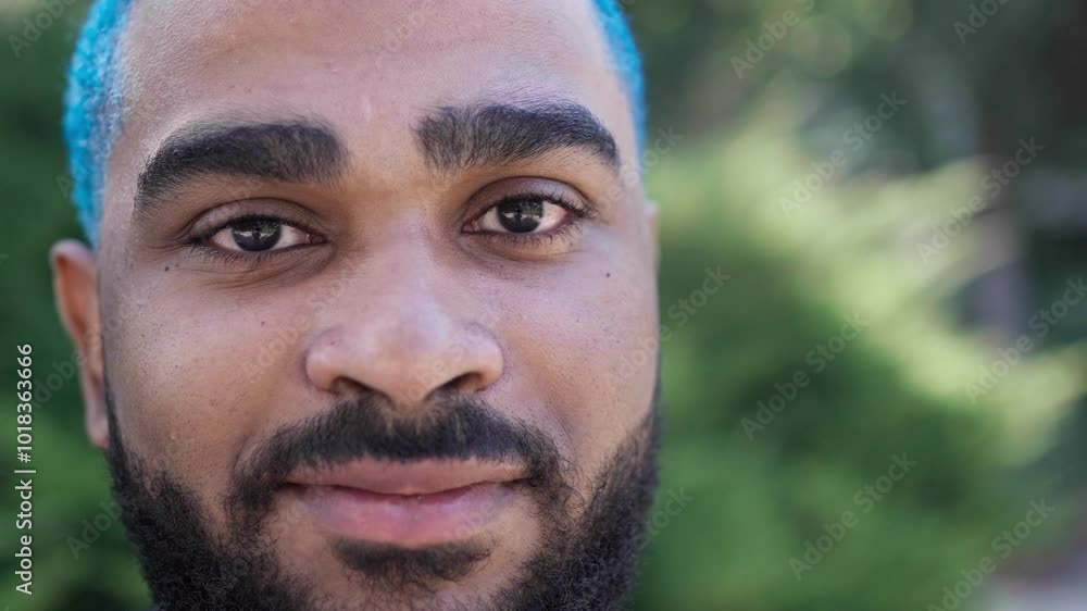 Extreme close-up of handsome cheerful black man with blue hair looking at camera, authentic gaze with green background. relaxed and chilling person_3.MOV Extreme close-up of handsome cheerful black man with blue hair looking at camera, authentic gaze with green background. relaxed and chilling person_3.MOV