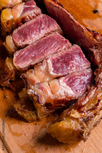 Bistecca di carne cotta sulla brace con cottura al sangue, scaloppata e servita con l'osso su un tagliere di legno in una braceria photo