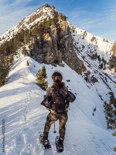 Snowshoe hiker admiring rocky mountain peak in winter Alps