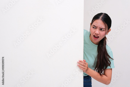 A woman peeking from behind a wall showing shocked face expression photo