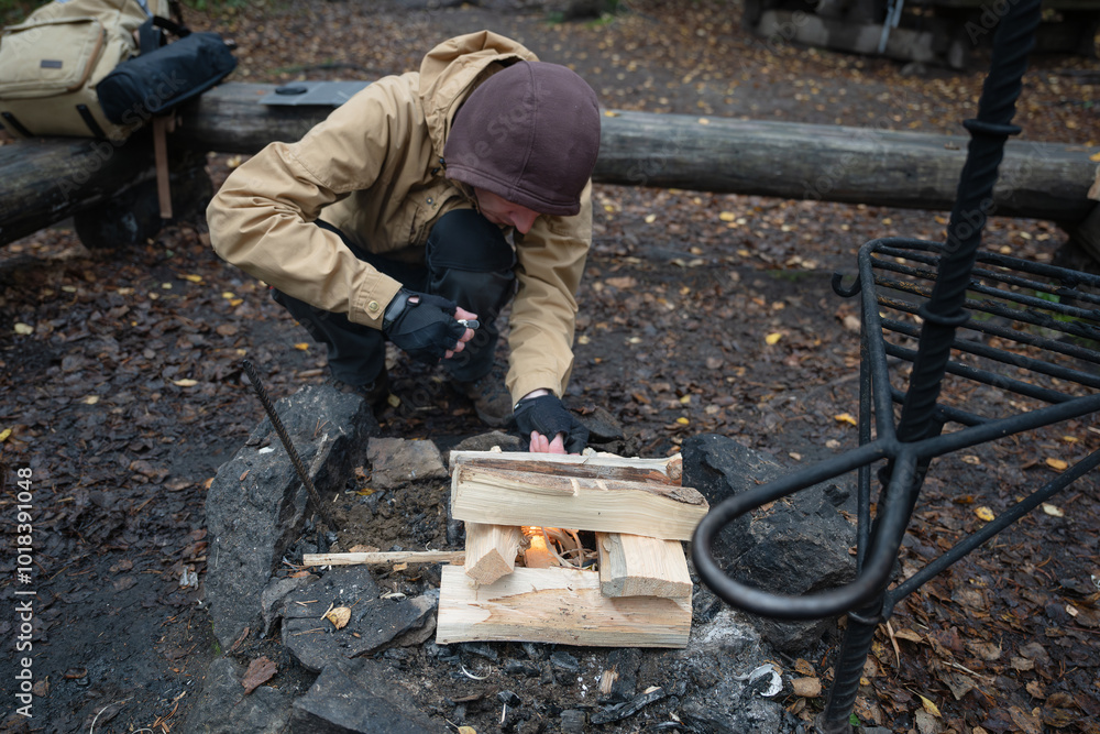 man starting a bonfire at picnic campfire in the forest man starting a bonfire at picnic campfire in the forest