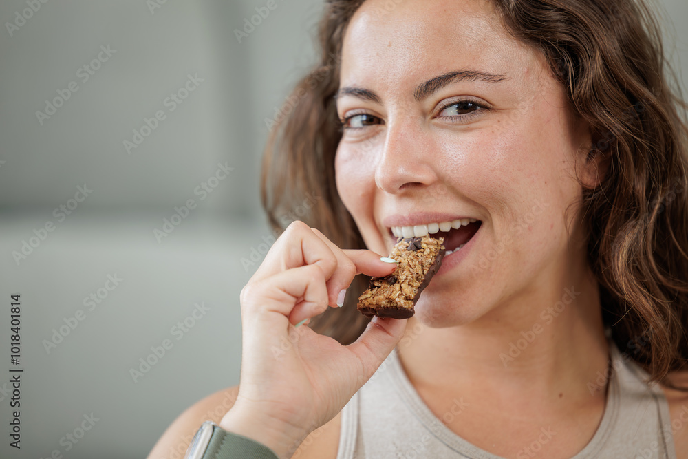 Portrait of a smiling young woman eating a protein bar with chocolate chips. Close up, copy space. Portrait of a smiling young woman eating a protein bar with chocolate chips. Close up, copy space.