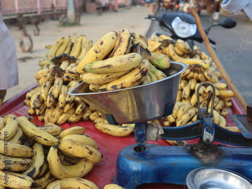 A banana vendor weighs and arranges bananas at his stall on Govardhan Parikrama Marg, capturing the vibrant atmosphere of local markets in a sacred setting. photo