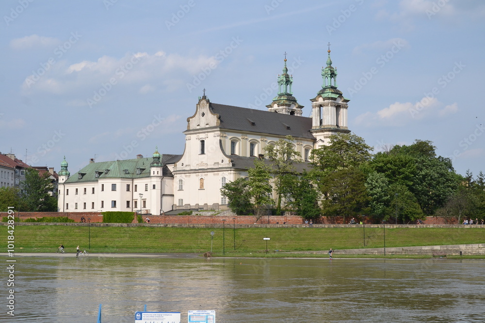 The photo of the Skalka Catholic Church in Kraków captures its baroque architecture standing resilient as the Vistula River floods nearby. The church's towers rise above the water. The photo of the Skalka Catholic Church in Kraków captures its baroque architecture standing resilient as the Vistula River floods nearby. The church's towers rise above the water.